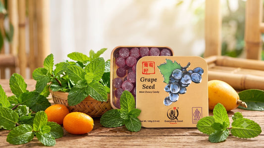 Everything Good Singapore's Grape Seed Mint Chewy Candy in an open gold tin, showcasing the grape seed pastilles alongside fresh mint leaves, kumquats, and a loquat to highlight its natural ingredients.