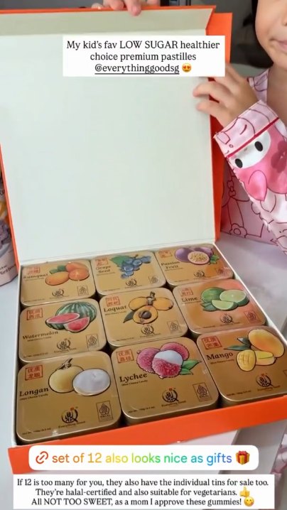 Child opening an orange gift box of 12 Everything Good Mint Chewy Candy tins in different fruit flavours