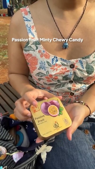 Creator holding an Everything Good Passion Fruit Mint Chewy Candy tin outdoors beside her crochet bag