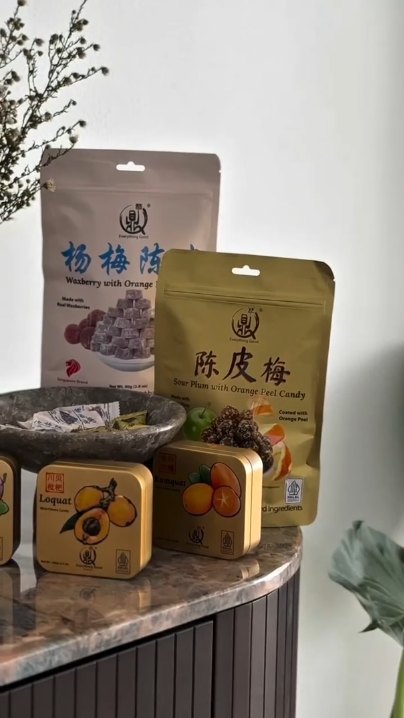 Everything Good Waxberry and Sour Plum with Orange Peel candy pouches with Loquat and Kumquat Mint Chewy Candy tins on a marble table