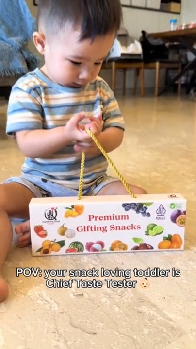 Toddler sitting on the floor with the Everything Good Premium Gifting Snacks box