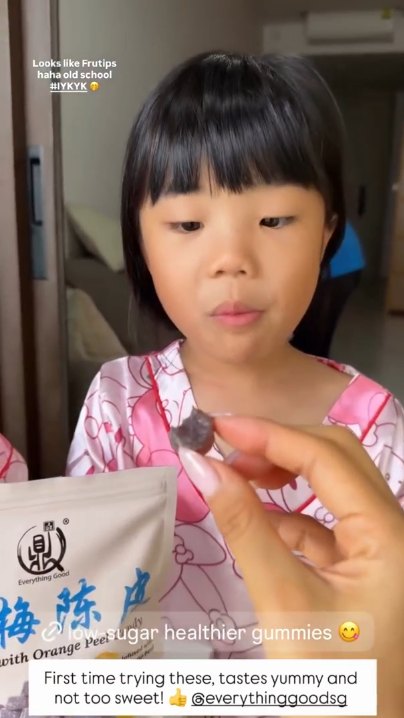 Child tasting Everything Good Waxberry with Orange Peel Candy, with the Waxberry pouch in front